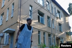 O angajată lângă o clădire a Spitalului Municipal de Boli Infecțioase pentru Copii, avariată în urma unui atac cu rachete din timpul nopții, la Kiev, pe 11 august 2026.