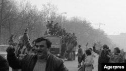 Manifestanți fericiți pe străzile Bucureștiului, pe așa-numitul bulevard Victoria Socialismului, pe 22 Decembrie 1989. În fundal se vede „Casa Poporului”, astăzi Palatul Parlamentului. Nicolae Ceaușescu a ordonat demolarea a mii de hectare din Bucureștiul istoric ca să ridice acest mastodont și bulevardul cu pricina.