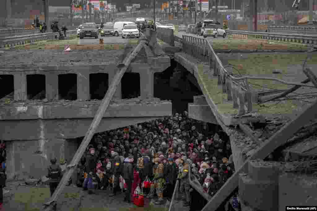 Szétlőtt híd alatt kelnek át az Irpiny-folyón a menekültek március 5-én Kijev külvárosában