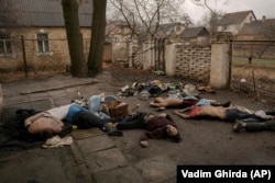The bodies of Bucha residents, all dressed in civilian clothes, some with their hands tied behind their backs, lie on the ground on April 3.