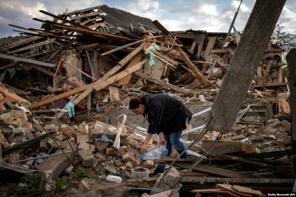 Në një foto të bërë më 3 maj, Anna Shevchenko ujit lulet që i mbijetuan bombardimit të shtëpisë së saj. Shtëpia u ndërtua nga gjyshërit e Shevchenkos. Në kopshtin e saj të luleve mbijetuan trëndafila, zambakë dhe bozhure.