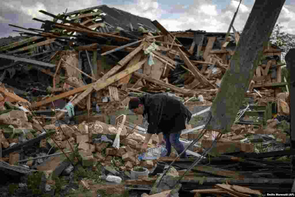 Anna Șevcenko udă florile care au rezistat bombardării casei sale, într-o fotografie făcută pe 3 mai. Casa a fost construită de bunicii Annei. Au supraviețuit trandafiri, crini, bujori și narcise.