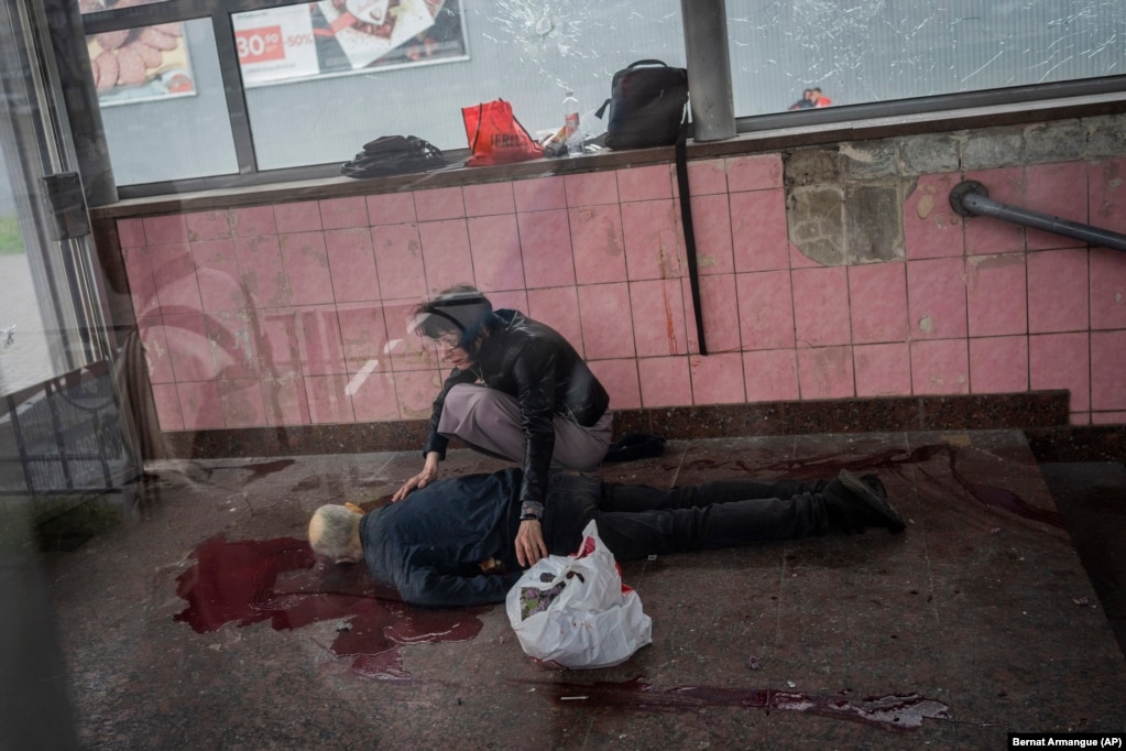 Një grua ulet në gjunjë pranë trupit të burrit të saj, Alexey, i cili u vra gjatë bombardimeve të qytetit lindor të Harkivit më 26 maj.