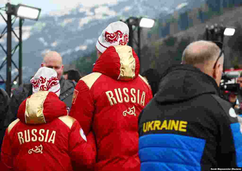 A member of the Ukrainian paralympic team passes Russian skiing gold medalists Anastasia Bagiian and Sergei Siniakin after the pair won gold on March 10.The 2026 Winter Paralympics opened on March 6 and will run until March 15.