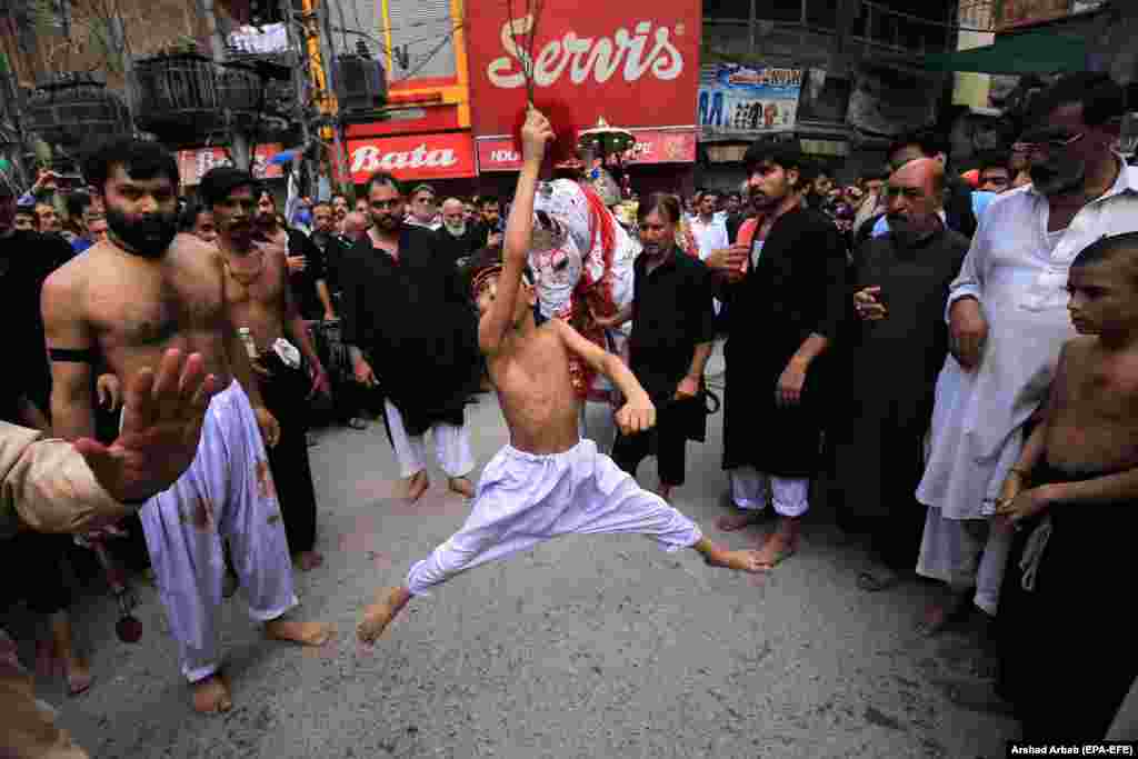 A young Shi&#39;ite Muslim boy holds knives attached to chains as he self-flagellates during an Ashura Day procession in Peshawar, Pakistan, on August 30. (epa-EFE/Arshad Arbab)