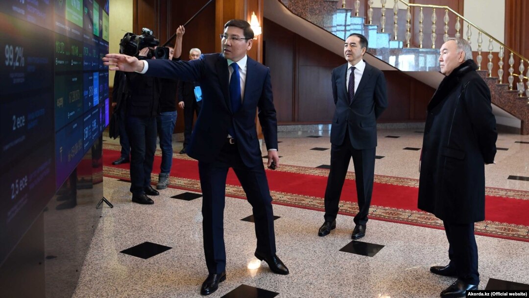 Қазақстан президенті Нұрсұлтан Назарбаев (оң жақта) пен премьер-министр Бақытжан Сағынтаевқа (ортада) вице-премьер Асқар Жұмағалиев сандық панельді көрсетіп тұр. Астана, 30 қаңтар 2019 жыл.
