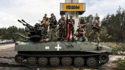 Militari ucraineni pozează într-o fotografie la intrarea în orașul Izium din regiunea Harkov, eliberat de sub ocupație rusă, 17 septembrie 2022.