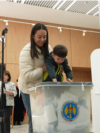 Moldova, A mother holds her child over a ballot box, Moldova election 2025
