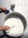 Një punëtor në një fabrikë të qumështit në Kosovë, gjatë kontrollit të produktit. 