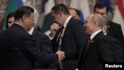 Russian President Vladimir Putin (right) shakes hands with Chinese President Xi Jinping at a Shanghai Cooperation Organization summit in Astana, Kazakhstan, on July 4.