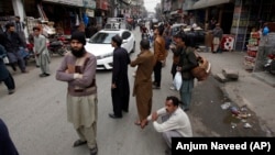 People stand outside their shops after a severe earthquake is felt in Rawalpindi, Pakistan, on January 31.