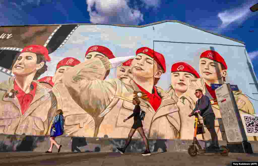 Pedestrians walk past huge graffiti depicting members of the Russian patriotic youth movement Yunarmiya in Moscow on May 25.