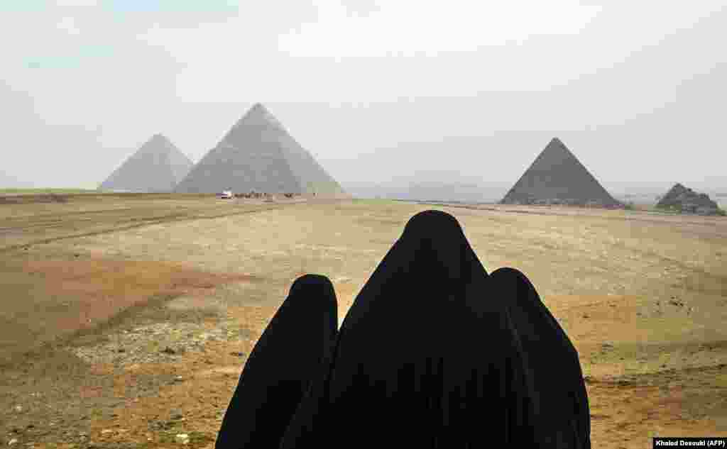 Women wearing veils look at the Great Pyramids of Giza on the southwestern outskirts of the Egyptian capital Cairo. (AFP/Khaled Desouki)