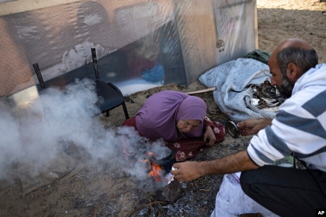 Familja Abu Jarad përgatit çaj në një kamp të improvizuar në zonën Muasi. 1 janar 2024.