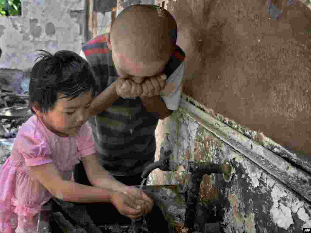 Оштағы қираған үйде су ішіп тұрған балалар. 21 маусым 2010 жыл.