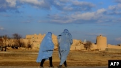 Two burqa-clad Afghan women walk on the outskirts of Herat.