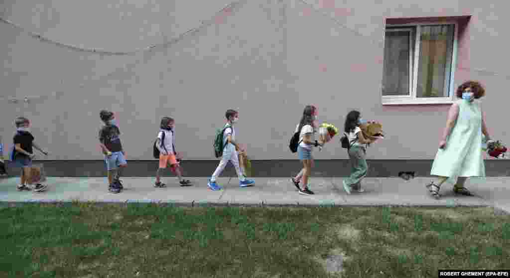 A teacher leads her class toward a medical checkpoint before entering classrooms during the first day of school at the George Enescu National College of Music in Bucharest.