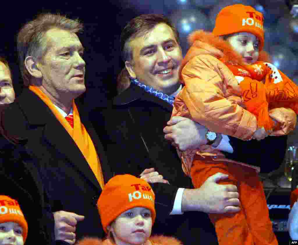 Ukrainian President-elect Viktor Yushchenko (left) and Georgian President Mikheil Saakashvili (right) greet residents of the Ukranian capital for the New Year on January 1, 2005 at Independence Square in Kyiv.