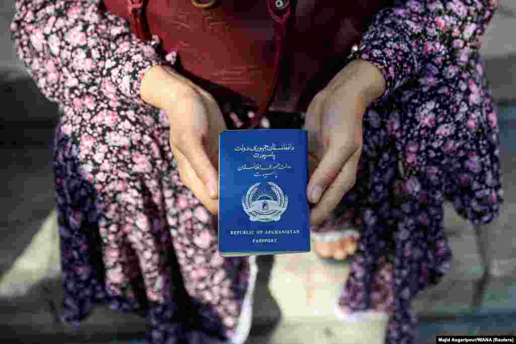 An Afghan refugee holds her passport in front of the German Embassy in Tehran ​in a bid to acquire refugee visas from the European country on September 1.