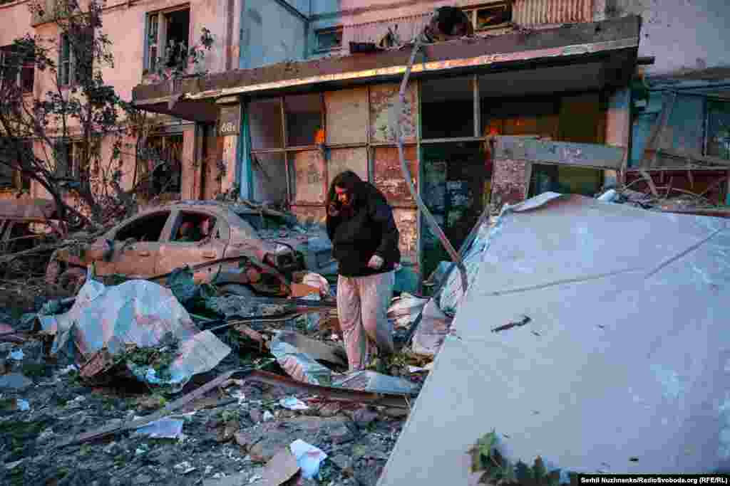 A woman walks through rubble at the entrance to a strike-damaged building in Kyiv. 
