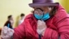 A woman uses a magnifying glass to fill out her ballot paper at a polling station in St. Petersburg.