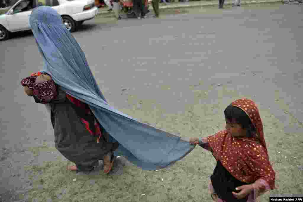 O femeie îmbrăcată în burqa merge cu copiii ei pe o stradă din Kabul. &nbsp;