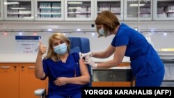 Egy állami kórház intenzív osztályán dolgozó nővért beoltanak a Pfizer-BioNTech Covid-19 vakcinájának első adagjával Athénban, 2020. december 27-én