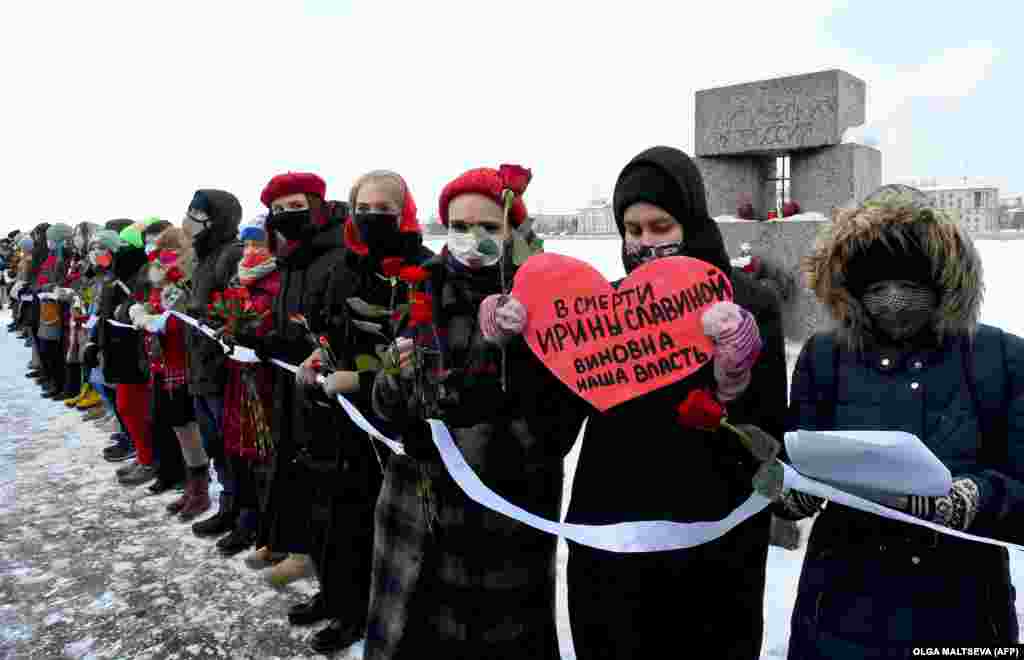 Российские женщины с розами и плакатами образуют живую цепь в День святого Валентина, чтобы выразить поддержку жене заключенного оппозиционера Алексея Навального и политическим заключенным в Санкт-Петербурге 14 февраля