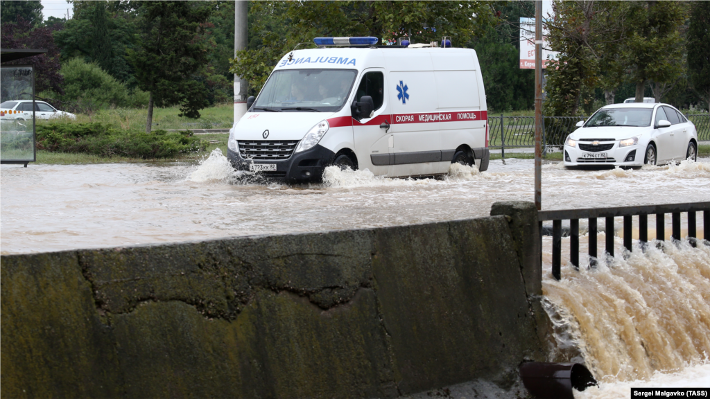 Машина швидкої допомоги пробирається крізь одну із затоплених вулиць міста