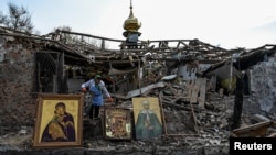 A woman collects Orthodox icons at the site of a church destroyed by a Russian missile strike in the village of Komyshuvakha on April 16.
