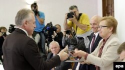 Բելառուս - Կենտրոնական ընտրական հանձնաժողովի նախագահ Լիդիա Երմոտշինան (աջից) նախագահական թեկնածուի նույնականացման քարտ է հանձնում Բելառուսի նախագահ Ալեքսանդր Լուկաշենկայի ներկայացուցիչ Միխայիլ Օրդային (ձախից), Մինսկ, 10-ը սեպտեմբերի, 2015թ․