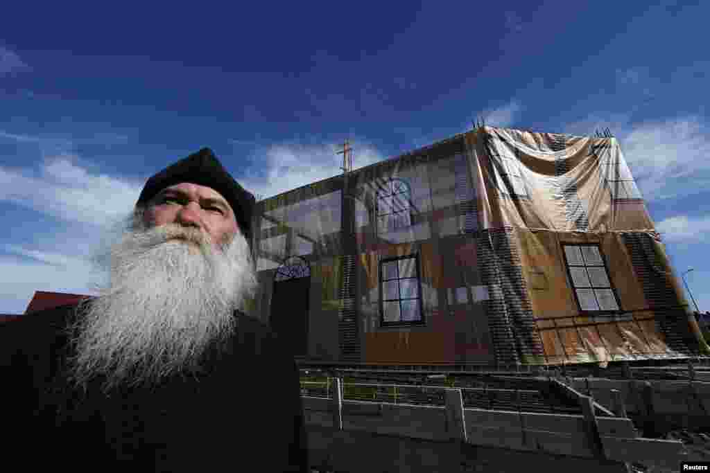 Archpriest Georgy Yefimov poses in front of the tarp-covered frame of a new church his community is building in Sochi. His community of &quot;Old Believers&quot;, who follow Russian Orthodox traditions dating from before reforms in the 17th century, lost their church to make way for the construction of the Olympic site. Efimov said getting building materials into the area had been nearly impossible while the Olympic construction wore on. (Reuters/Eric Gaillard)