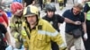 Injured Kyiv resident identified as Yaroslav Bazylevych (right) follows Ukrainian rescue workers carrying the body of one of his daughters, who was killed along with her two sisters and their mother during a missile attack in Lviv on September 4.