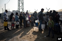 Anëtarët e familjes Abu Jarad presin në radhë për ujë në një kamp të improvizuar në zonën Muasi, në jug të Gazës.1 janar 2024.