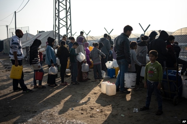 Anëtarët e familjes Abu Jarad presin në radhë për ujë në një kamp të improvizuar në zonën Muasi, në jug të Gazës.1 janar 2024.
