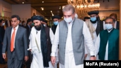 Pakistani Foreign Minister Shah Mahmood Qureshi walks with Mullah Abdul Ghani Baradar (second left), the leader of the Taliban delegation, upon his arrival in Islamabad for talks on August 25, 2020.