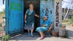 Două femei au ieșit dintr-un adăpost antiaerian al unei fabrici de sticlă, în orașul Lisichansk din regiunea Luhansk, Ucraina, 5 iulie 2022.
