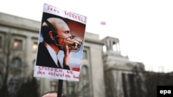 A Ukrainian demonstrates with a poster depicting Russian President Vladimir Putin with a muzzle and text calling on German Chancellor Angela Merkel to "stop the mad dog" in front of the Russian embassy in Berlin on March 17. 