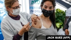Egészségügyi alkalmazott beadja a Pfizer/BioNTech-vakcinát egy terhes nőnek Tel-Avivban, 2021. január 23-án