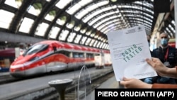 Një pasagjer tregon certifikatën e COVID-19 në një platformë të një stacioni treni në Milano, Itali më 16 prill 2021.
