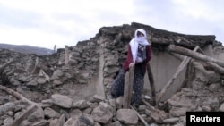 A woman stands on the ruins of a destroyed house in Elazig Province in eastern Turkey.