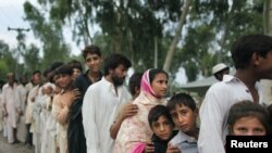 Flood victims jostle for position in a line to receive evening food handouts from a charity at a road-side tent camp near Nowshera, in Khyber Pakhtunkhwa Province.