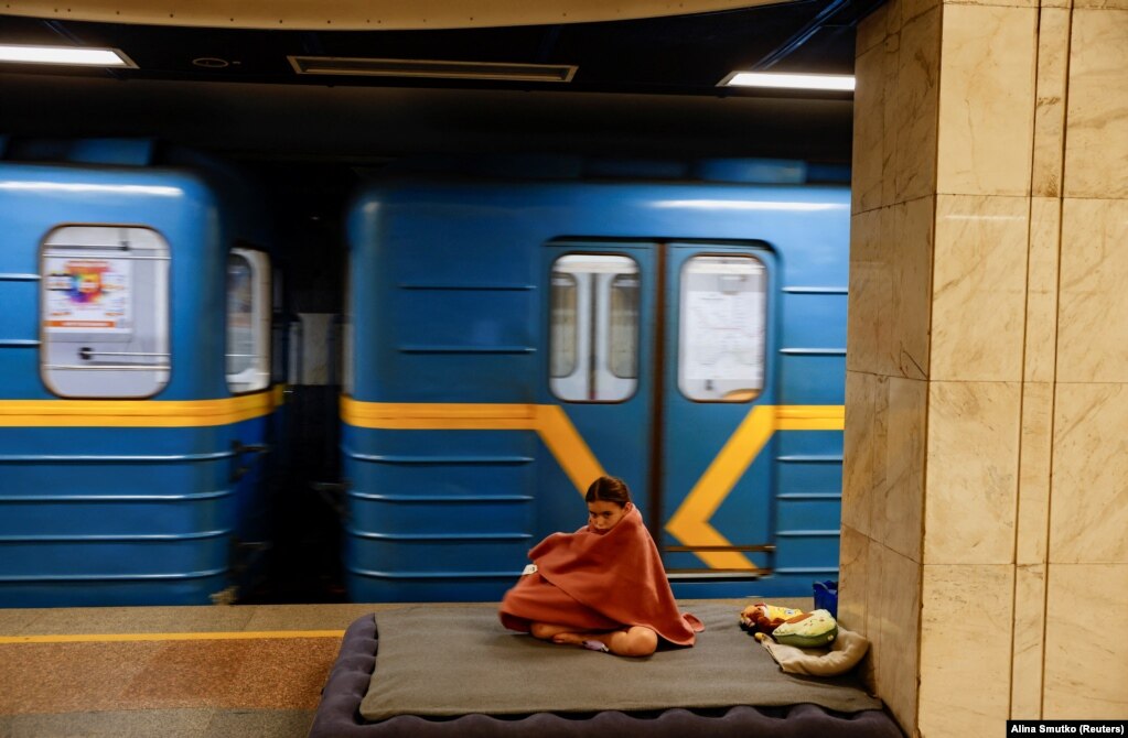 Një vajzë e mbuluar me batanije pranë një treni, gjatë strehimit në një stacion metroje në Kiev, më 8 korrik.