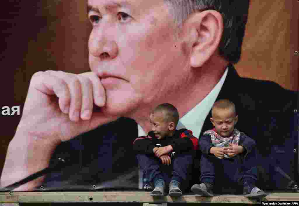 Boys sit on a bench under a campaign banner for the Social Democratic Party of Kyrgyzstan featuring an image of former Kyrgyz President Almazbek Atambaev in the village of Arashan, some 20 kilometers from Bishkek. (AFP/Vyacheslav Oseledko)