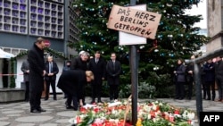 German Chancellor Angela Merkel (2nd L), German Interior Minister Thomas de Maiziere (3rd L) and Berlin's mayor Michael Mueller (L) stand at a makeshift memorial for the victims of an attack in front of the Kaiser Wilhelm Memorial Church in Berlin on December 20.