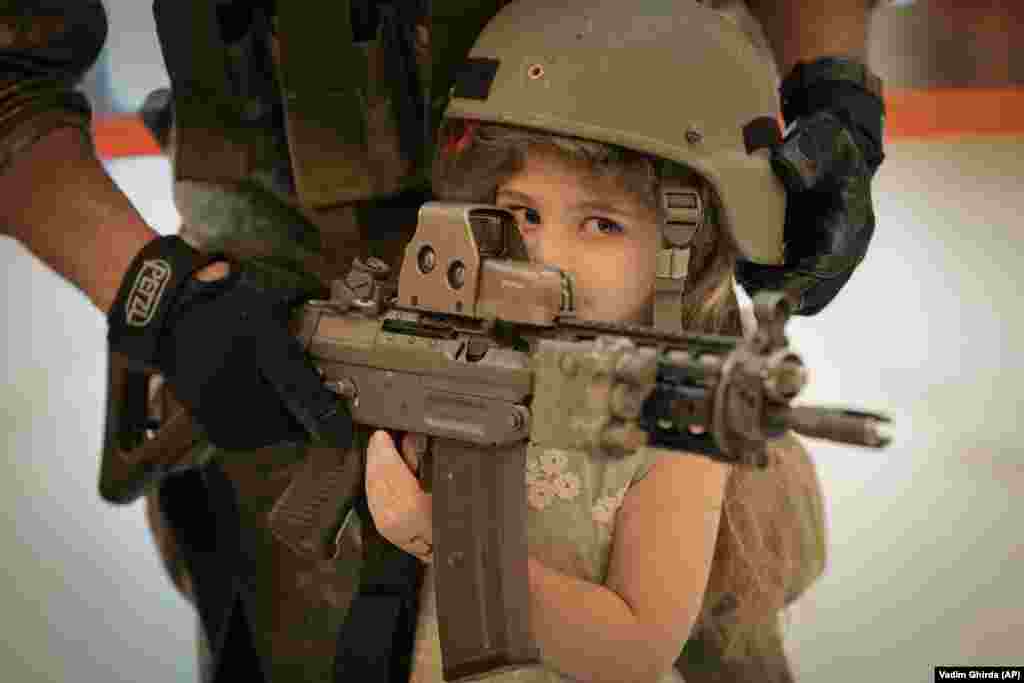 Devojčica pozira sa oružjem na štandu specijalne jedinice Vojske Ruminije u Palati parlamenta. Palata je druga po veličini administrativna zgrada na svetu posle Pentagona, a 1. juna građani i građanke su iskoristili priliku slobodnog ulaza na Međunarodni dan deteta