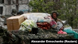 Az oroszbarát csapatok katonáinak tankja egy utcán egy lerombolt lakóépület mellett az ukrán–orosz konfliktus során Popaszna városában, a Luhanszki régióban, Ukrajnában 2022. május 26-án