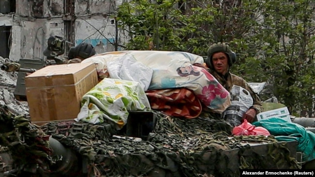 Российские солдаты в городе Попасная в Луганской области с вещами, которые, по словам местной жительницы Алины Коренюк, похищены из ее дома. Фото 26 мая 2022 года