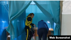 Процесс голосования на избирательном участке №529 в Алматы. В кабину для голосования зашли два человека. 5 июня 2022 года