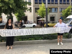 Активистки в Берлине перед зданием «Европа-Хаус» держат плакат: «Мы - простой народ, мы — не террористы». 5 июня 2022 года